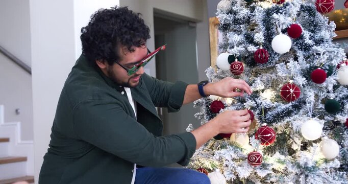 African American couple at home decorating flocked tree, woman handing ornaments
