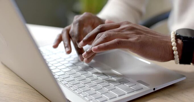 Hands are moving from poised into rapid typing on silver laptop at desk, completing work