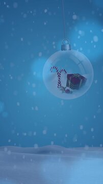 Animation of snow falling over christmas baubles in winter scenery
