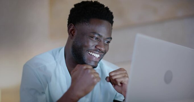 Man in his 20s at home seeing laptop notification, shifting focus into celebrating win, clapping