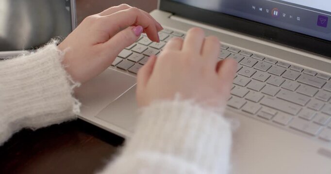Hands are typing on laptop at desk, playback controls appearing and right hand reaching to control