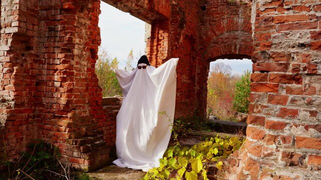 Ghost in haunted brick ruin during autumn Halloween