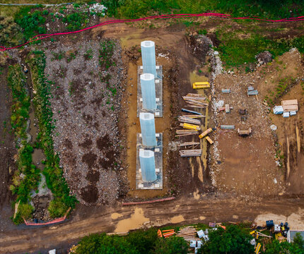 Aerial view of construction site featuring four aligned concrete bridge piers surrounded by dirt, construction materials, and vegetation in Lubenec, Usti nad Labem Region, Czechia.