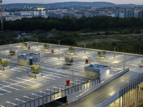 Aerial view of Parking P+R Gorka Narodowa with modern parking spaces, concrete structures, and small trees at dusk in Krakow, Wojewodztwo malopolsk, Poland.