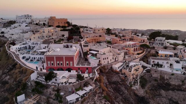 Aerial view of white buildings in Fira Santorini during a peaceful golden sunset