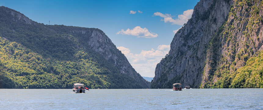 Tourist boats navigating the Danube River through the dramatic Iron Gates gorge, surrounded by imposing rocky cliffs