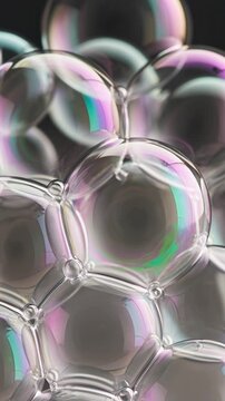 Iridescent soap bubbles with colorful rainbow reflections on dark background macro shot