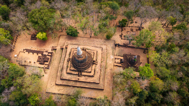 Aerial view of the ancient stupas and ruins of Si Satchanalai Historical Park surrounded by lush trees in Si Satchanalai, Sukhothai, Thailand.