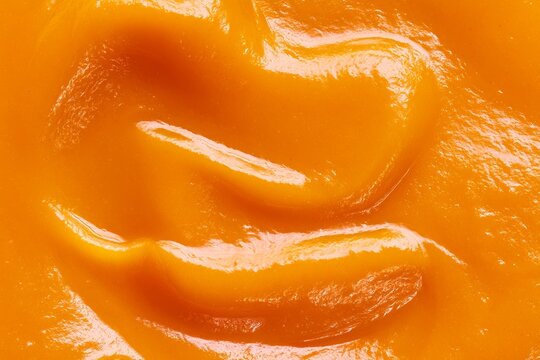 Smooth texture of orange puree close up in a kitchen setting during food preparation