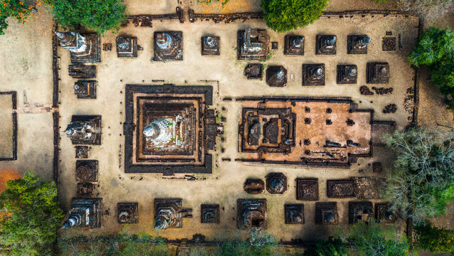 Aerial view of the ancient ruins and stupas at Si Satchanalai Historical Park, featuring stone structures and temple grounds surrounded by lush trees in Si Satchanalai, Sukhothai, Thailand.
