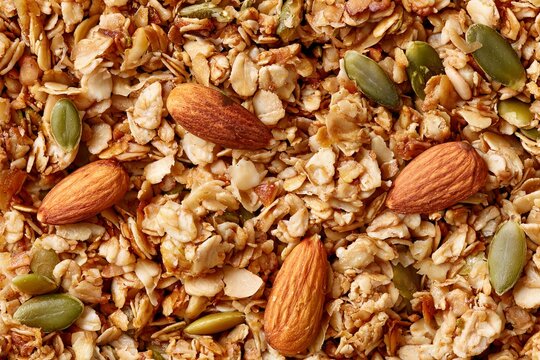 Granola mix with oats, nuts, and seeds on a flat surface in a kitchen setting