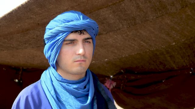Marrakech, morocco. August 9, 2026. Young man with a serious expression wearing a traditional blue turban and clothing. Authentic portrait of a berber person in north africa