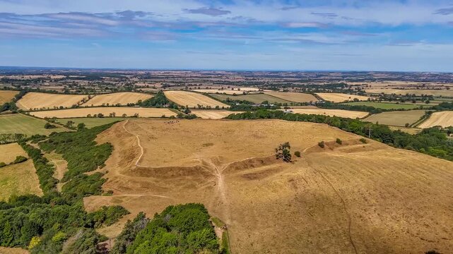 An aerial view rotating at a distance from the remains of the Iron Age Hillfort in rural Leicestershire, UK in late summertime