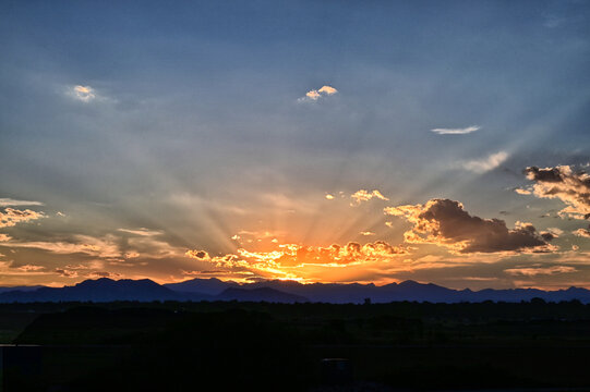 Vibrant orange sunset with sun beams over the mountains near Denver CO
