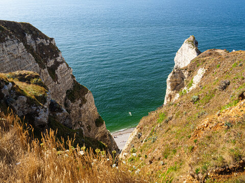 Vista de la playa de arena blanca y mar turquesa desde los acantilados de roca  de alabastro de Etretat caminando por la costa de Normand&iacute;a en Francia en un d&iacute;a de verano 2022 