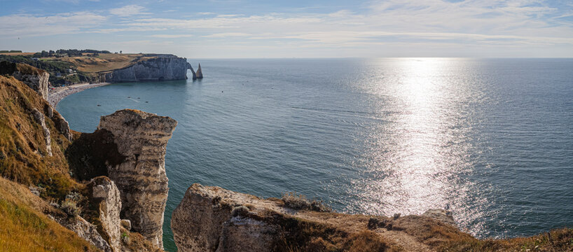 Vista panor&aacute;mica a&eacute;rea de la costa normanda de Etretat sobre el mar azul, con un arco de piedra al fondo y rocas de tiza t&iacute;picas de los acantilados en un atardecer de verano, viajando Francia 2022