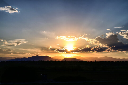 Vibrant orange sunset with sun beams over the mountains near Denver CO
