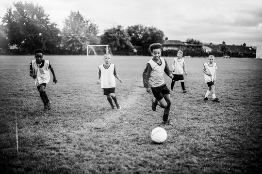 Children playing soccer on a grassy field in black and white
