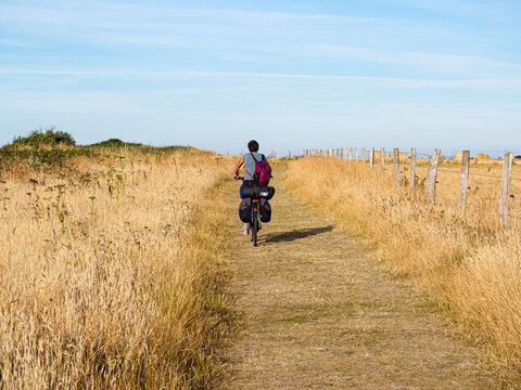 Hombre en una bicicleta por el campo amarillo hacia el horizonte azul en Etretat la Normand&iacute;a Francesa. Viajando en verano de 2022