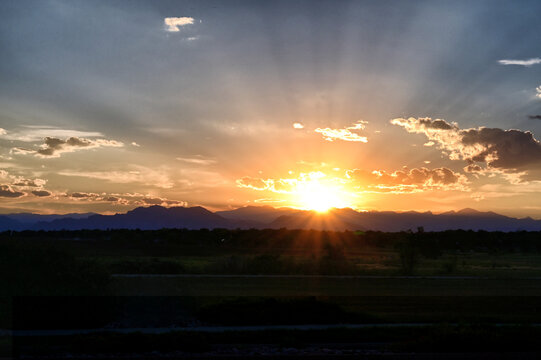 Vibrant orange sunset with sun beams over the mountains near Denver CO