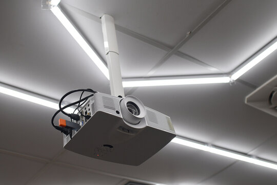 Down view of ceiling mounted digital projector in modern office or conference room.