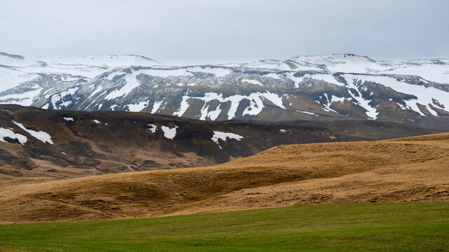 Icelandic landscape farmland showing snow capped mountains and green hills. Iceland
