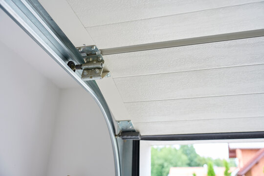 Garage door roller running inside metal track beside sectional panels
