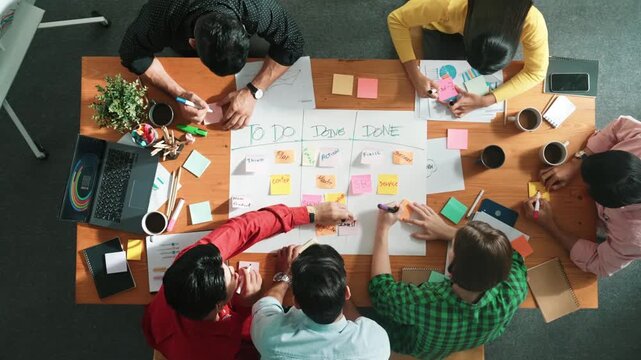 Top down aerial view of business team making scrum task board at meeting room. Group of people writing at paper and sticky notes for making kanban board to manage work flow. Time lapse. Convocation.