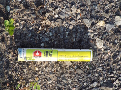 Gatineau, Quebec, Canada &ndash; June 30, 2026: A discarded yellow and white "Good Supply" cannabis pre-roll packaging tube lies on a gravel ground surface on Bd Saint-Ren&eacute; E.