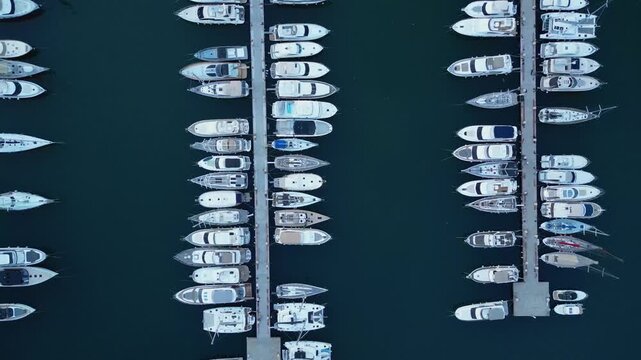 Top-down aerial drone view flying over wooden pier and sailboats moored in rows at harbor marina in Sanremo, Italian Riviera, Liguria, Italy