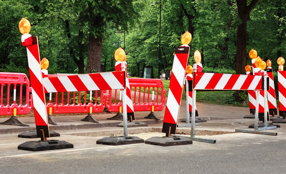 Red and white warning barricade at a road construction excavation. Safety barrier for a street repair hazard over a hole in the asphalt