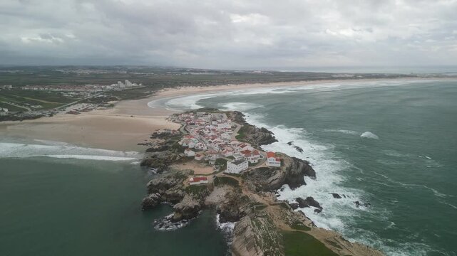 Aerial view of Baleal Island with its coastal village, sandy beaches, and rocky cliffs surrounded by the Atlantic Ocean in Peniche, Leiria District, Portugal.