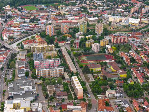 Aerial view of residential apartment blocks, a distinctive water tower, a sports field, and urban infrastructure in Breclav, South Moravian Region, Czechia.
