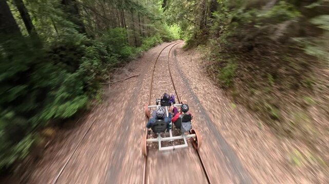 A couple enjoys an electric railbike ride over old railroad tracks through redwood trees and bridges in Fort Bragg California.