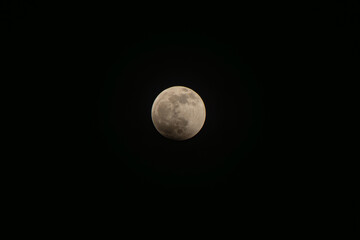 Lunar eclipse phenomenon illuminating the night sky with the full moon gradually entering earth's shadow, creating a subtle darkening effect © VICTOR A ARGUELLO