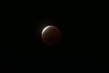 Blood moon appearing during a partial lunar eclipse, creating a stunning celestial phenomenon in the dark night sky, showcasing space and astronomy © VICTOR A ARGUELLO