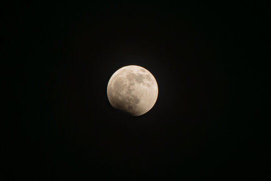 Earth's shadow beginning to cover the full moon, showing the fascinating astronomical phenomenon of a partial lunar eclipse against the dark night sky