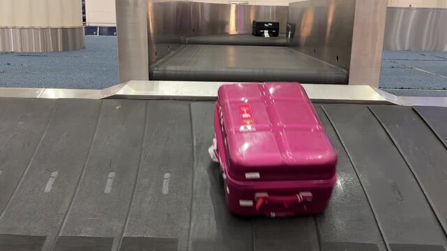 Passenger suitcases on baggage carousel inside modern airport terminal, representing air travel, tourism and luggage collection after journey, shot handheld. High quality 4k footage