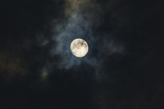 Full moon in the night sky with clouds