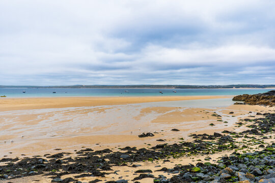 Sandy beach at low tide with turquoise water on an overcast day.
