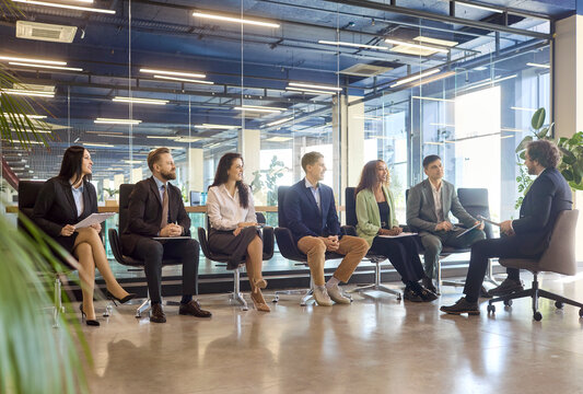 Employees and coworkers attend seminar training workshop meeting. Seated team listens to manager, speaker and trainer in a modern office. Focus on skills. Teamwork and learning concept stated.
