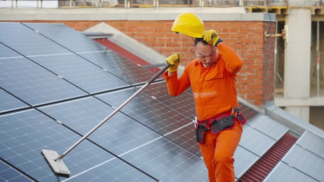 Exhausted technician cleaning solar panels on a roof