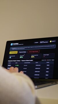 Educator at a laptop using AI software for automated bulk grading of student essays while scanning for unauthorized student AI usage and plagiarism