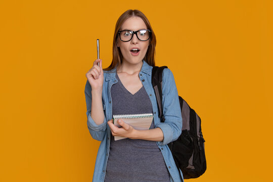 Surprised college student raising pen after getting an idea