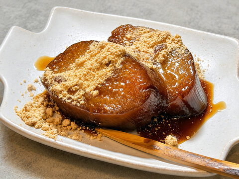Slices of traditional Japanese dessert Akumaki with kinako powder and kuromitsu syrup on a ceramic plate