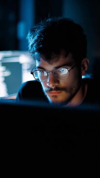 Focused Programmer with Glasses Coding in a Dimly Lit Room