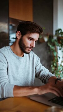 Focused Man with Beard Typing on Laptop in Modern Workspace
