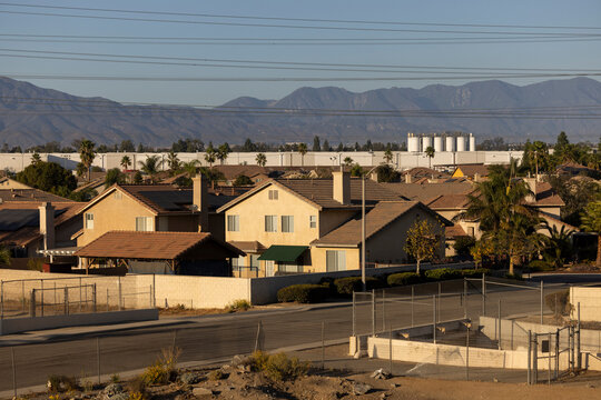 Afternoon sun shines on single family homes and industry  in the Declezville neighborhood of Fontana, California, USA.