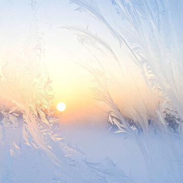 Beautiful winter frost patterns on glass window with golden sun rising in sky
