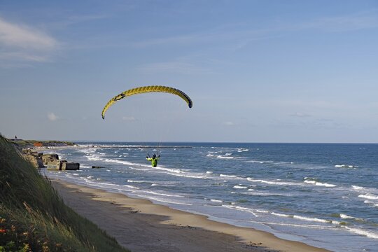Paraglider soaring over the beach along the coastline with a view of the sea and the waves, Sport, Holiday, Lokken, Jutland, Denmark